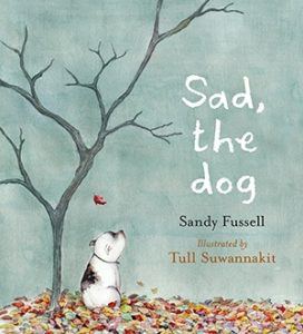 Book cover of Sad, the Dog. A tiny pitbull dog looks up into the sky in a leaf-covered backyard, under a tree, all alone