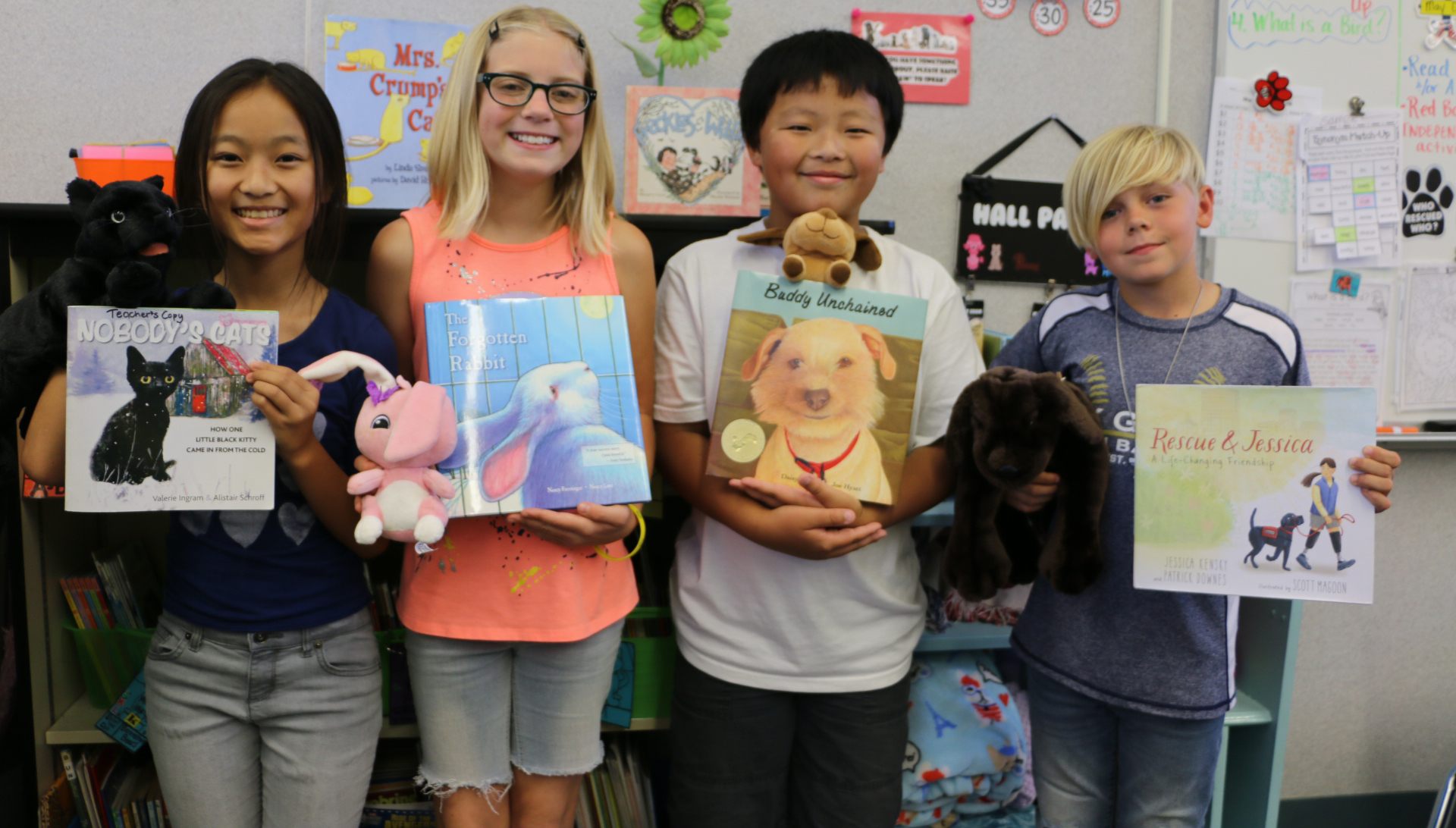 Students holding books and stuffed animals