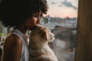 Beautiful Black woman kissing her dog on the head