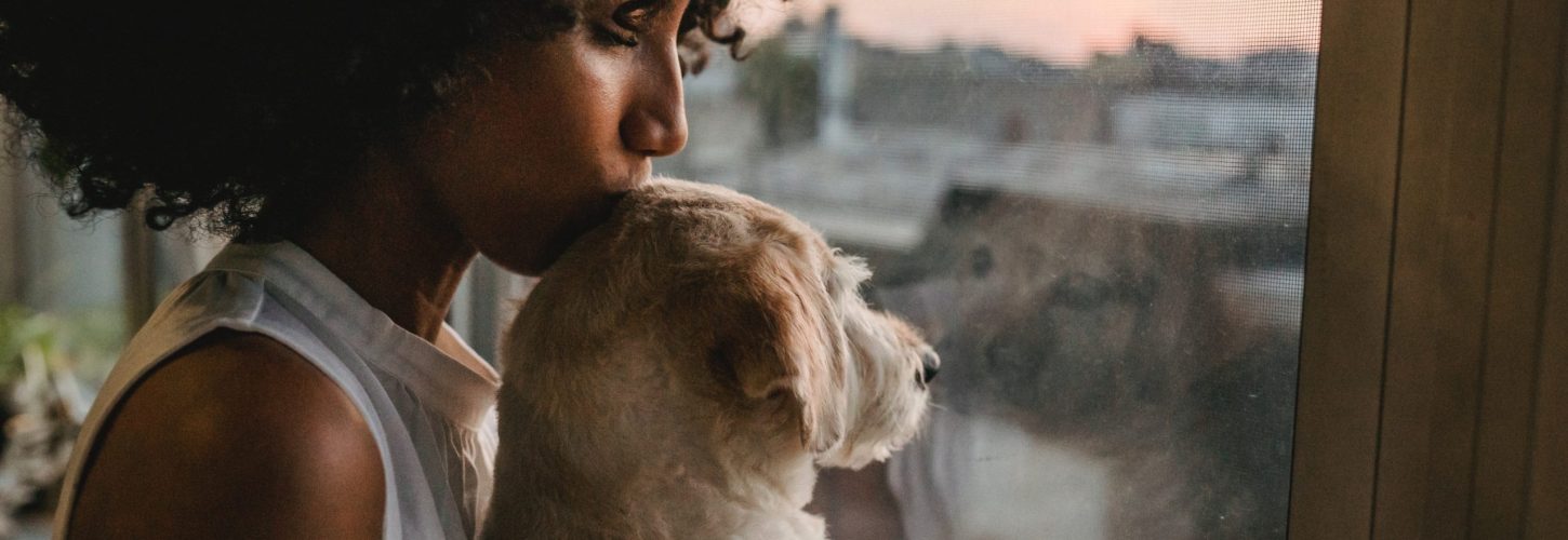 Beautiful Black woman kissing her dog on the head