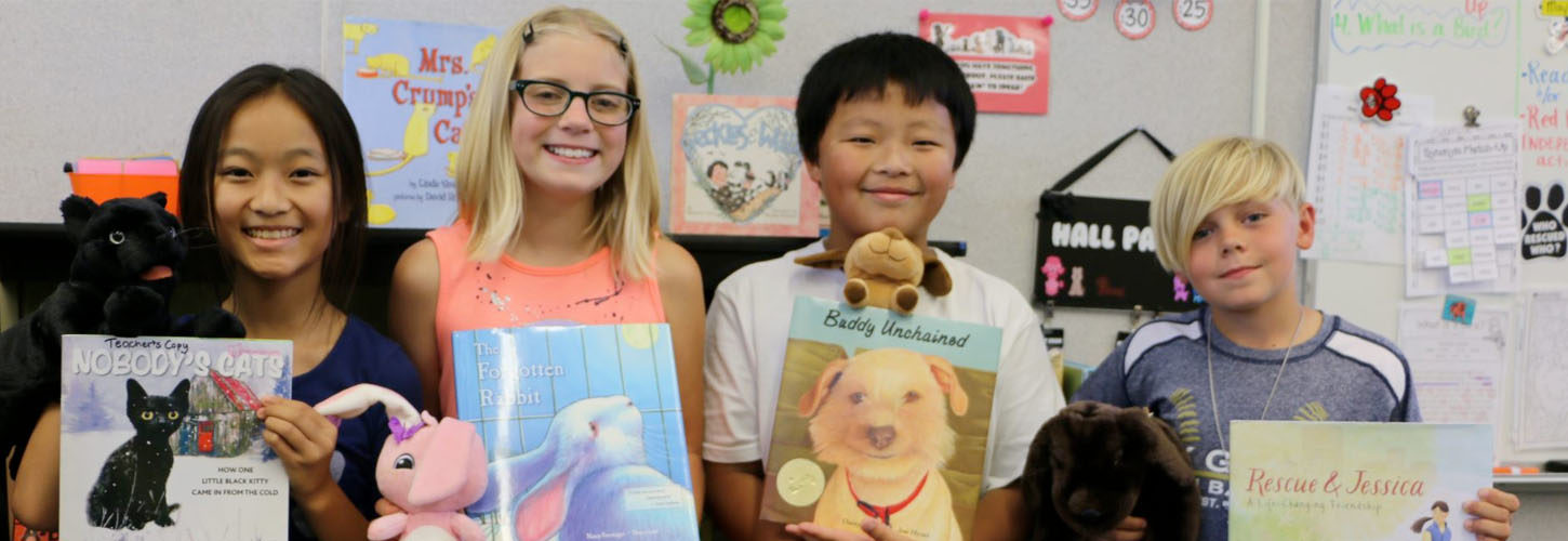Students holding books and stuffed animals