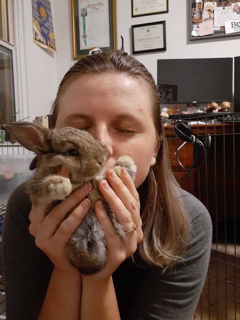 Caty is holding a brown baby bunny named Kahlua and kissing her face