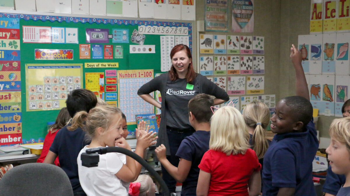 An educator stands in front of an elementary school classroom