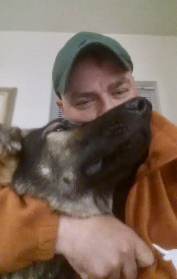 A German Shepherd gets kisses from his male owner