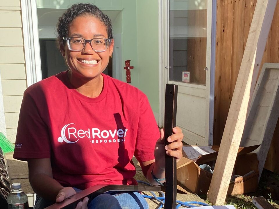 A woman in a red RedRover Responders volunteer tshirt assembles furniture
