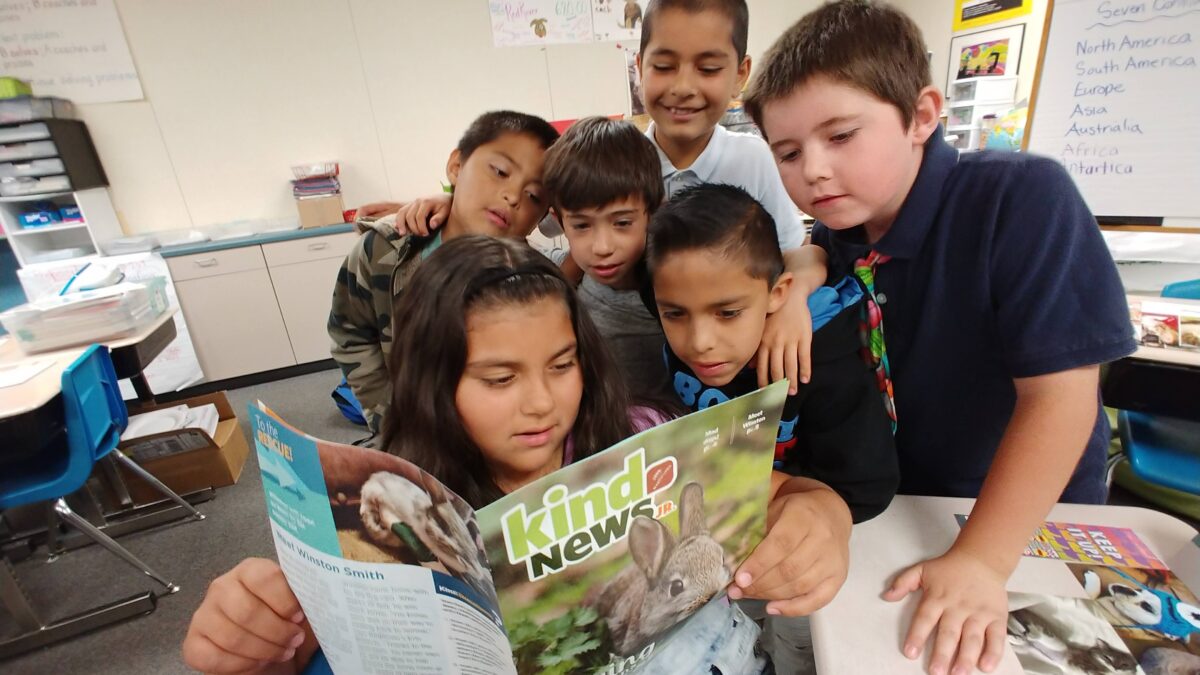 children reading a magazine together in a classroom