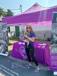woman holding dog in front of purple table and tent