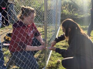 two women cutting a wire fence