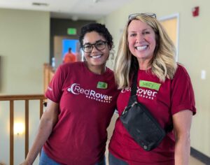 Two RedRover Responders staff in red shirts, one woman with dark, curly hair and glasses, and another woman with blonde hair and a crossbody bag