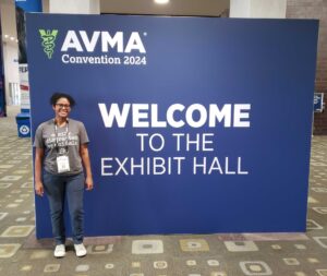 woman wearing glasses standing in front of AVMA exhibit hall sign