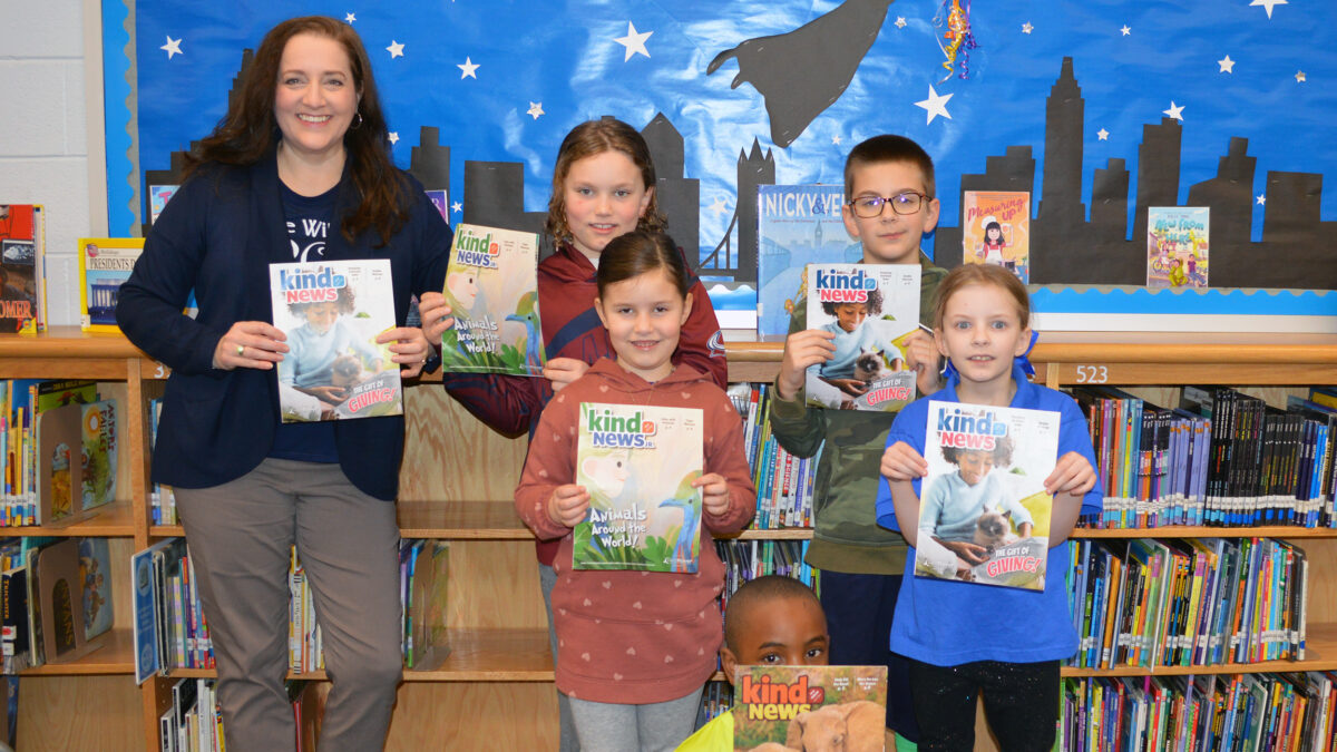 Prince William SPCA's Melissa Korzuch and children in a classroom holding copies of Kind News magazine