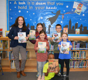 Prince William SPCA's Melissa Korzuch and children in a classroom holding copies of Kind News magazine