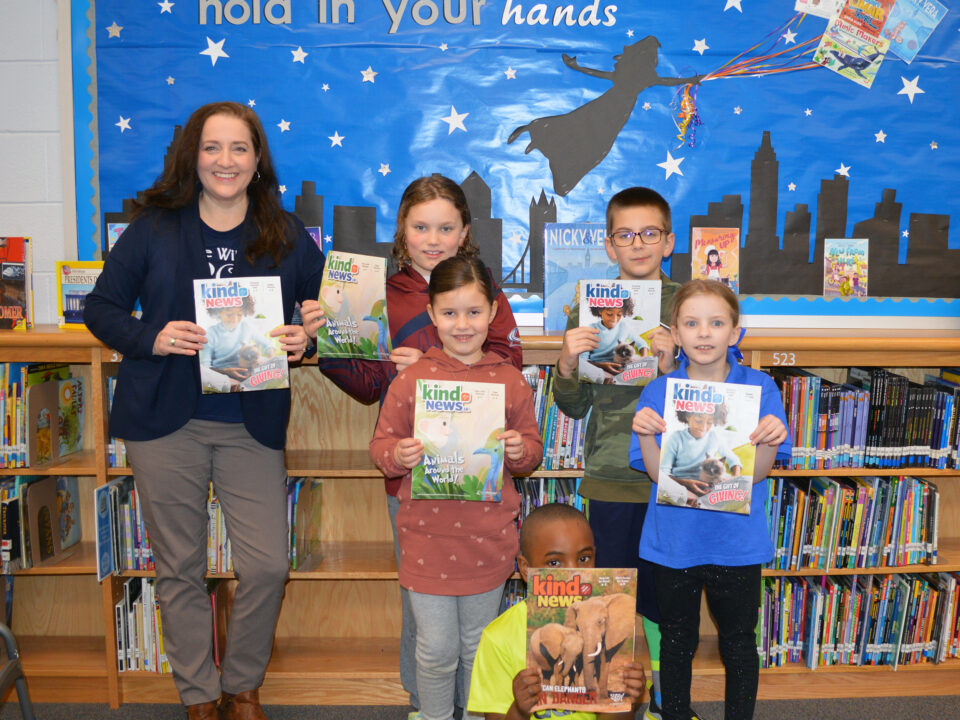 Prince William SPCA's Melissa Korzuch and children in a classroom holding copies of Kind News magazine