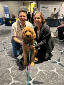 two women and brown curly dog at the National Organization for Victim Advocacy conference