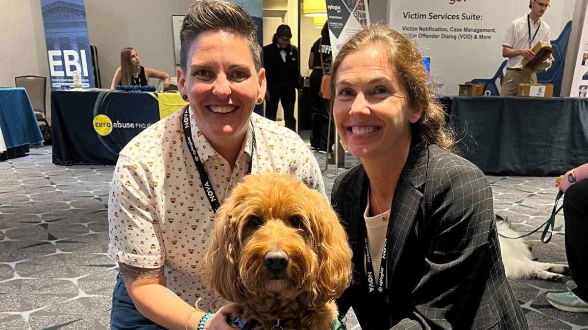 two women and brown curly dog at the National Organization for Victim Advocacy conference