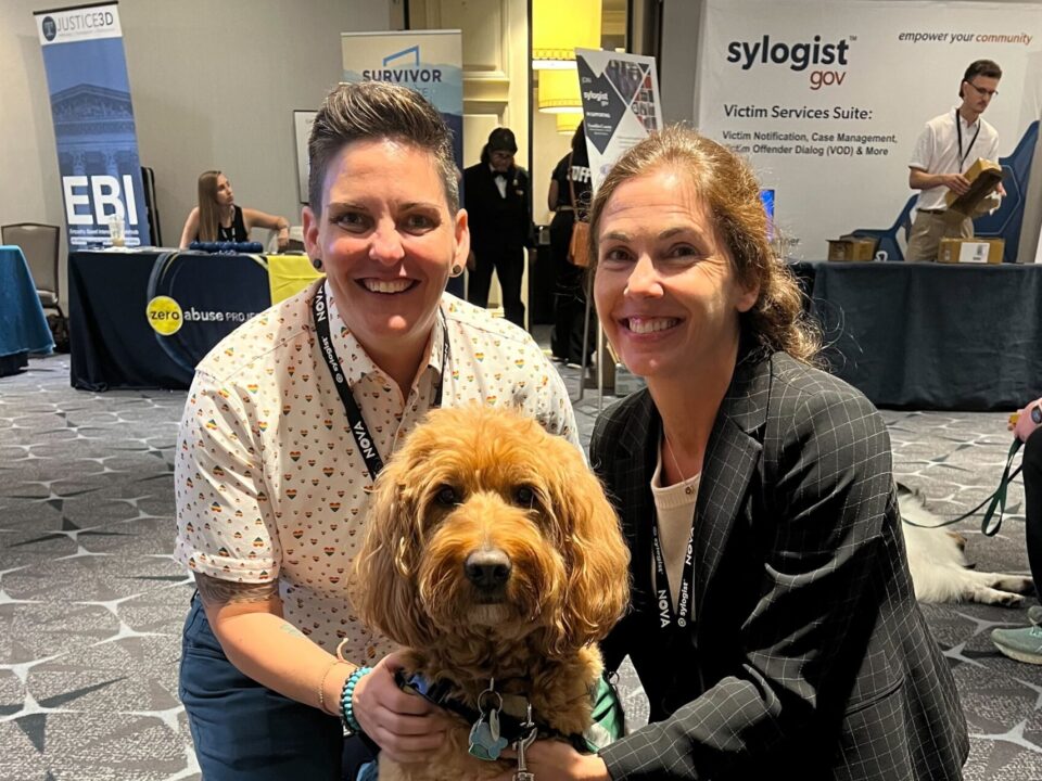 two women and brown curly dog at the National Organization for Victim Advocacy conference