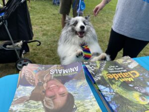 Dog jumps up onto table displaying issues of Kind News, RedRover's magazine for kids