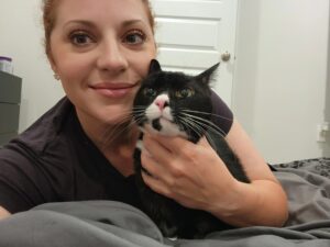 woman hugs black and white cat with green eyes