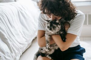 DFTP - woman holds tortoiseshell cat in bedroom