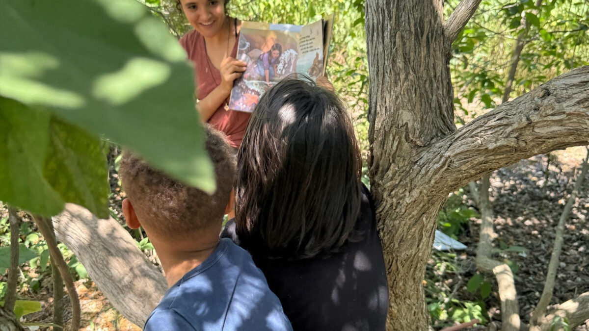 The Forest School in South Texas hosts a RedRover Readers book reading while children sit in a tree