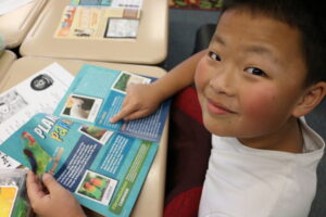 Classroom kid reads Kind News magazine