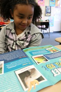 A classroom kid reads Kind News magazine