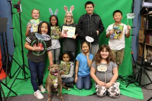 A classroom poses with Kind News magazine and a dog