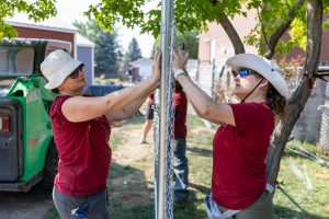 RedRover Responders volunteers install chain-link fencing at a domestic violence shelter build